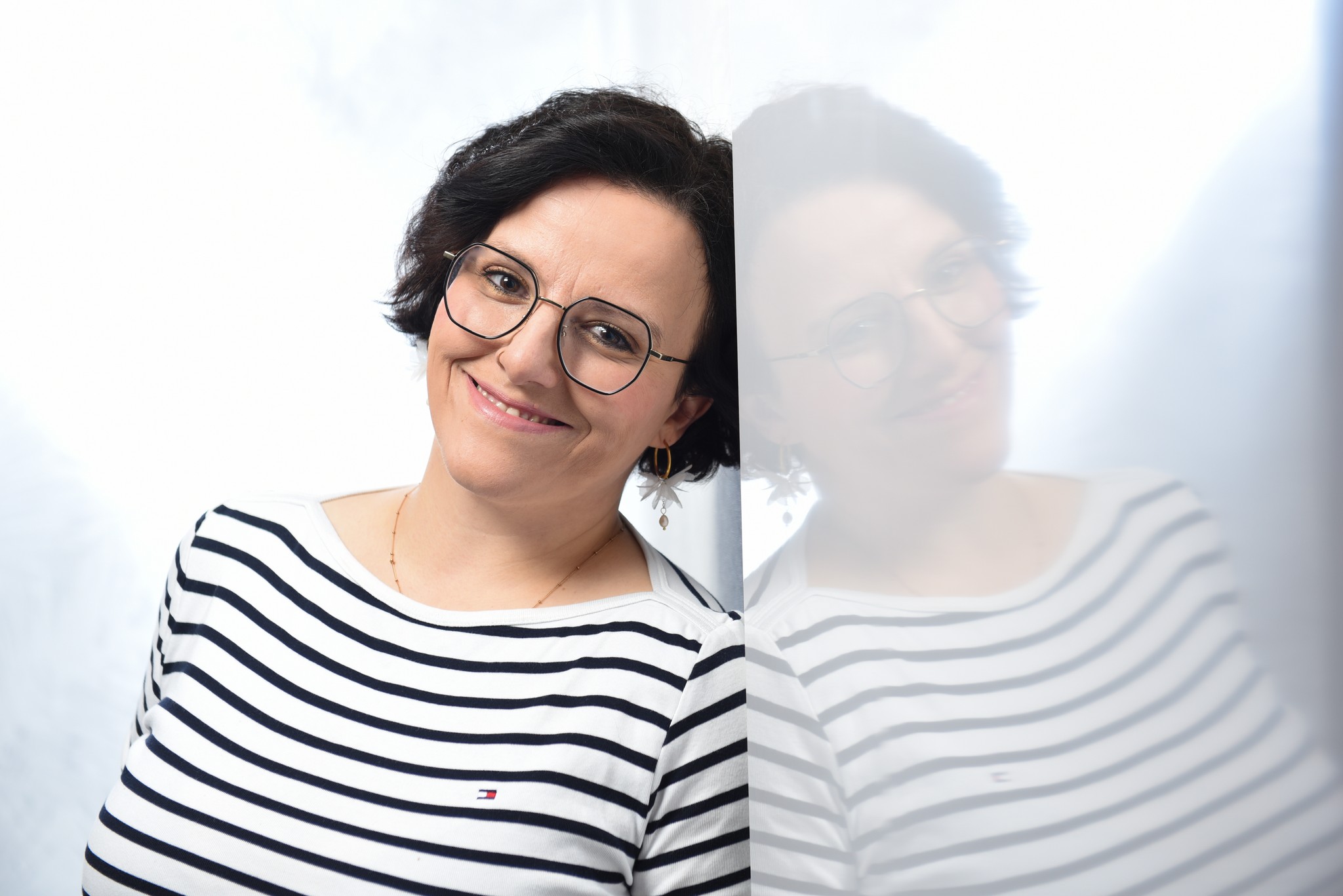 Sonja Sträßer mit warmem Lächeln an einer Glasfläche